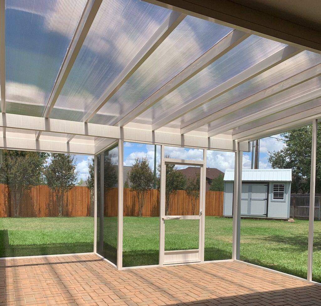 Covered pergola with polycarbonate and screened in over a paver patio
